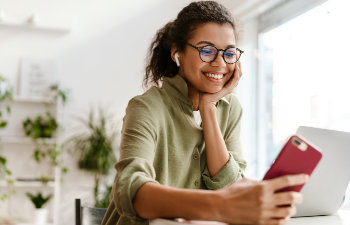 smiling girl with glasses looks at a smartphone, 